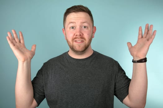 Man leaning forwards staring at the camera in shock, surprise or amazement over a grey studio background