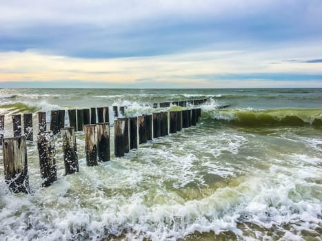 Wild ocean sea landscape with waves collapsing against wooden poles