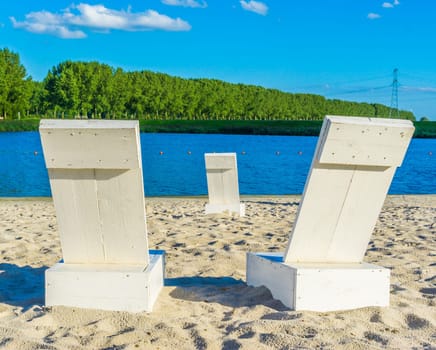 couple of white beach seats at the beach lake