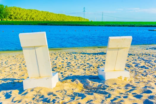 two white beach seats at a sandy beach river landscape
