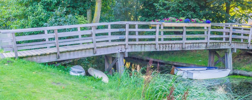 big wooden bridge with boats in a river landscape