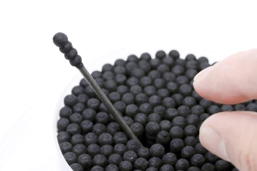 Black cotton swabs with the finger on the white background
