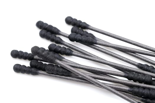 Black cotton swabs on a white background, close up