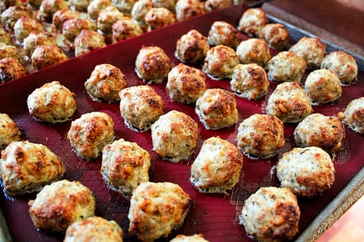 Baked meatballs on a red silicon mat.