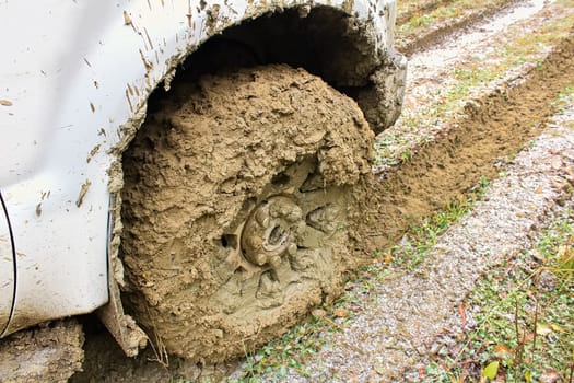 The wheel of a vehicle incased in mud.