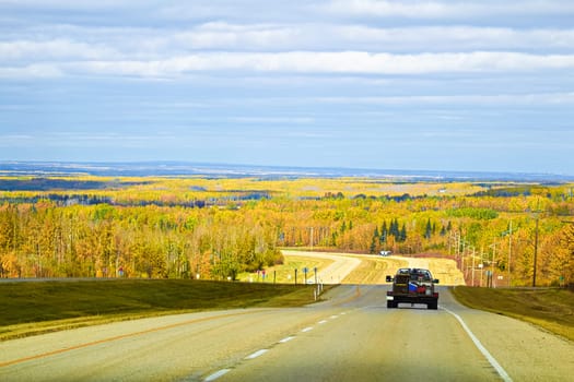View of a vehicle traveling along a highway in the autumn.