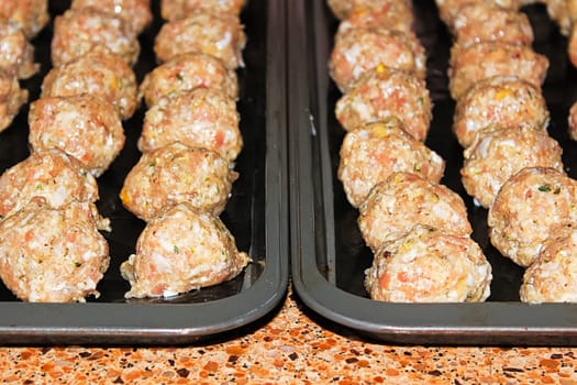 view of raw turkey pine nut meatballs on cookie sheets.