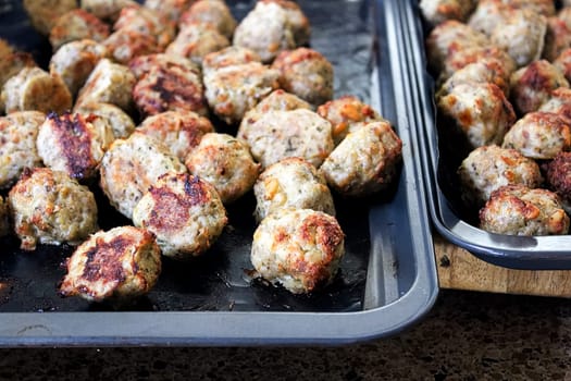 Freshly baked meatballs about to be taken off a cookie sheet.