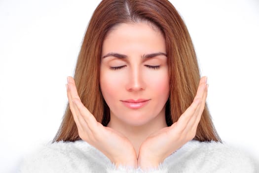 Beautiful woman with closed eyes meditates with her hands in front of her face