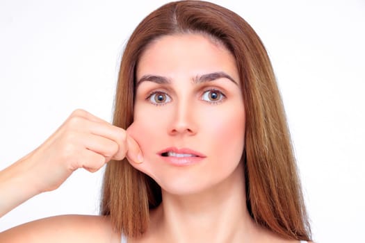 Beautiful woman pulls on her cheek with her fingers