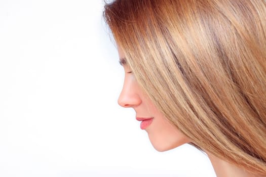 Beautiful woman face with long blond hair from the side looks down
