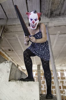 Crazy clown with saw, murderer and halloween