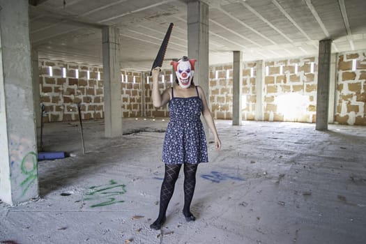 Crazy clown with saw, murderer and halloween