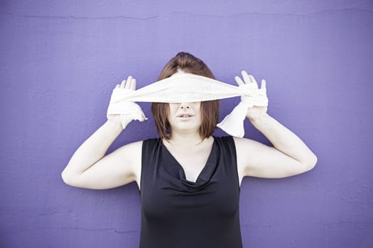 Girl covering eyes with tape on wall, mystery