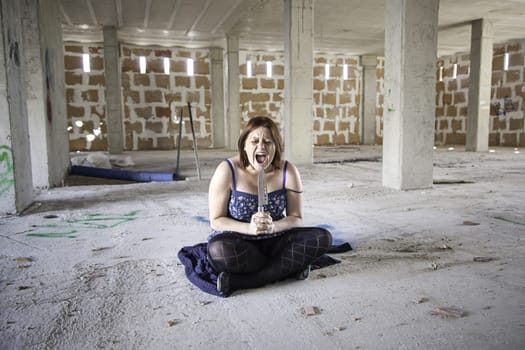 Woman with knife in abandoned house, fear and halloween