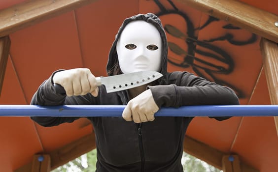 Murderer in playground with mask and knife, halloween