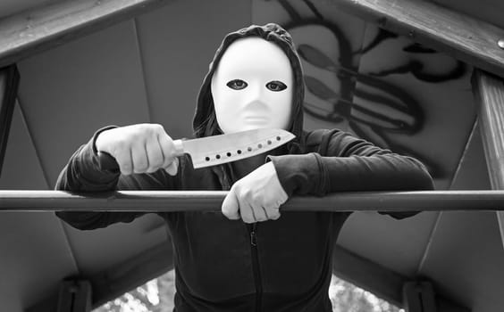 Murderer in playground with mask and knife, halloween