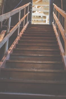 An old wooden staircase in an old barn leads upwards.