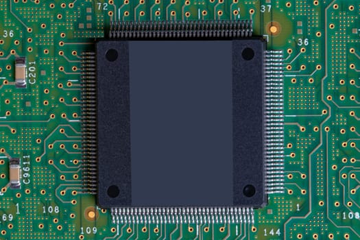 Green technology background. Closeup detail image of a big chip with a lot of legs on green digital electronic circuit board texture background. PCB. Space for your design on chip.