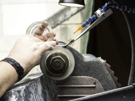 Man sharpening glass with steel lathe, work and industry