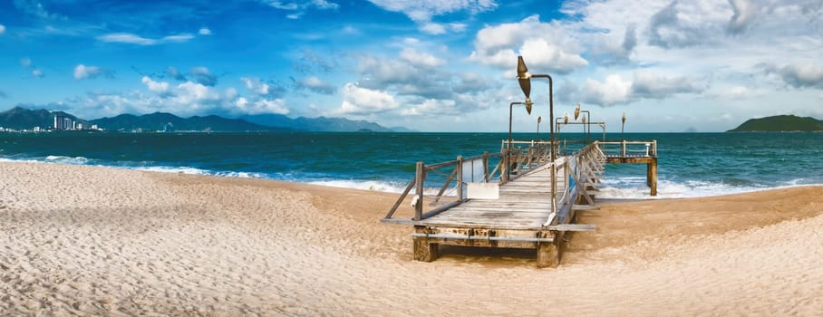 Scenic view of Nha Trang beach at sunny day. Beautiful tropical landscape. Pier on the foreground. Panorama