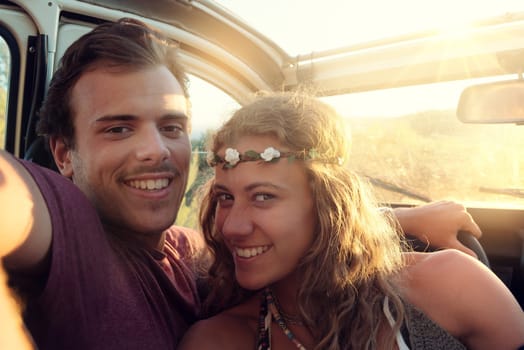 Happy young couple in a car enjoying the beautiful sunset in countryside.