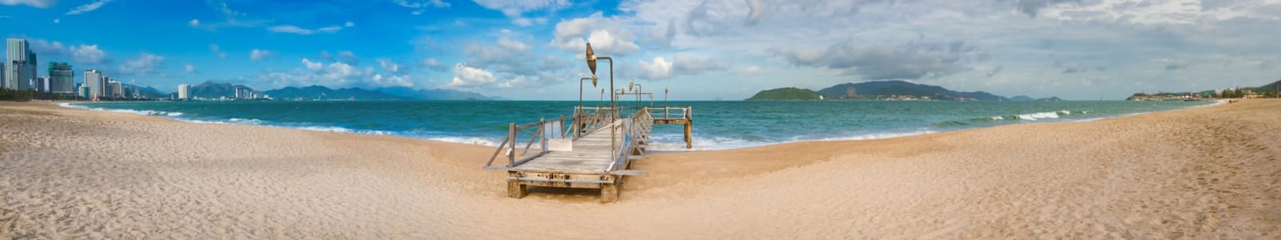 Scenic view of Nha Trang beach at sunny day. Beautiful tropical landscape. Pier on the foreground. Panorama