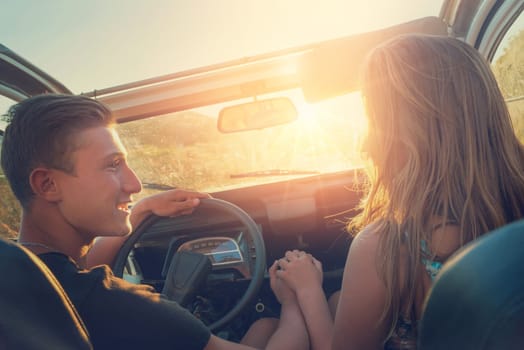 Happy couple in a car enjoying sunset.