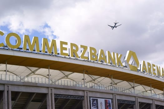 Frankfurt, Germany - August 11, 2018: A plane flying over the stadium roof and the logo of the Commerzbank Arena, the home of the football club Eintracht Frankfurt on August 11, 2018 in Frankfurt..