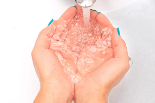Female hands under running water in the sink