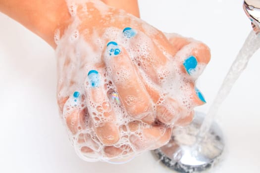 Female hands under running water in the sink