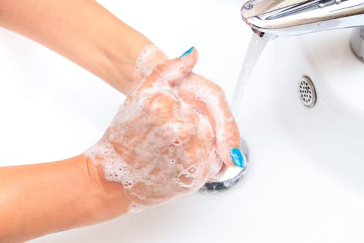 Female hands under running water in the sink