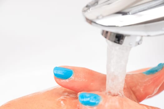 Female hands under running water in the sink