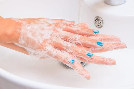 Female hands under running water in the sink