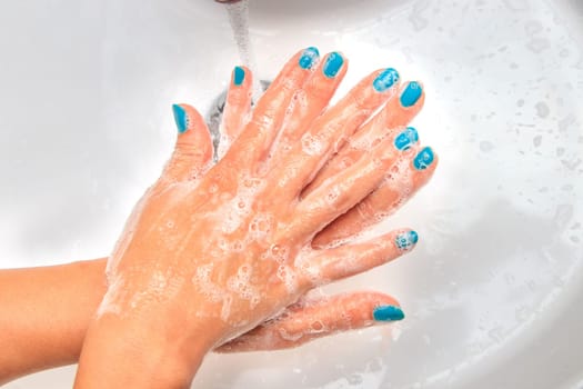 Female hands under running water in the sink