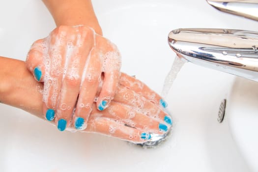 Female hands under running water in the sink