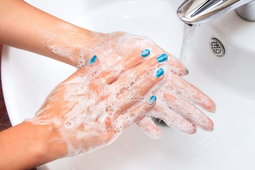 Female hands under running water in the sink