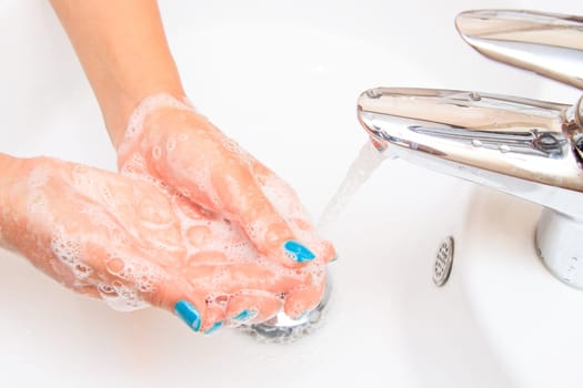 Female hands under running water in the sink