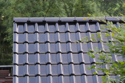 Modern roof with PVC coated black roof tiles with brick effect.