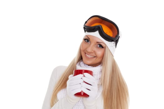 Young woman in ski glasses and winter warm clothes with red cup stands on a white background. Winter sports.