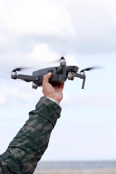 Hand catching drone aircraft in sky background, camera operator concept
