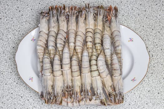 Frozen seafood background. Closeup of frozen fresh raw tiger shrimps on a plate. Top view. Concept healthy food.