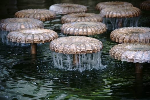 Mushroom cap-shaped fountains and jets of a fountain over which the water trickles....