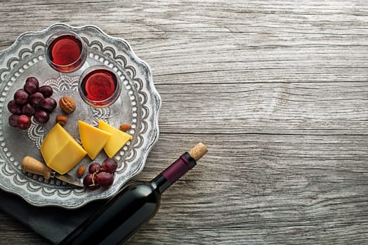 Excellent red wine bottle, wineglass and food on a rustic wooden table: traditional winemaking and wine tasting concept - Image