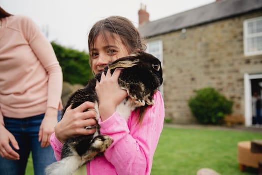 Young female child excited and happy to be holding a pet rabbit. She is smiling and looking at the camera.