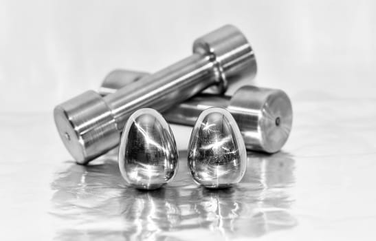 Metal dumbbells and steel eggs, the concept of sports training and the achievement of muscle strength.