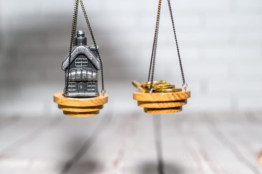 Stack of coins and a small house on the scales. The concept of choice, cash savings and purchase of real estate