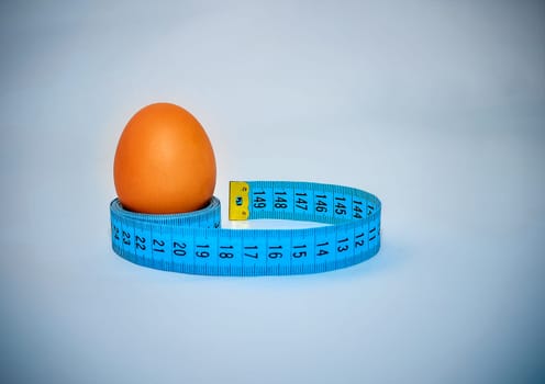 Egg wrapped in blue measuring tape, slimming concept.