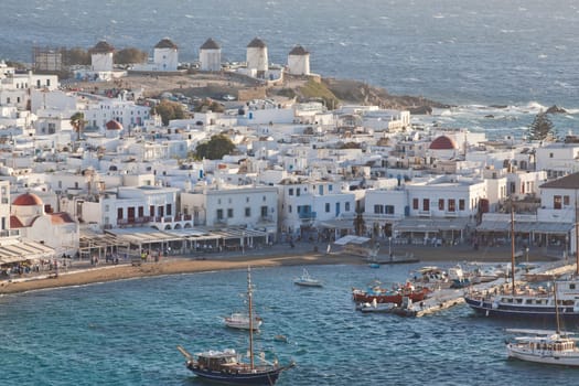 panoramic view of the Mykonos town harbor with famous windmills from the above hills on a sunny summer day, Mykonos, Cyclades, Greece