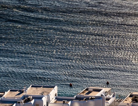panoramic view of the Mykonos town harbor with famous windmills from the above hills on a sunny summer day, Mykonos, Cyclades, Greece